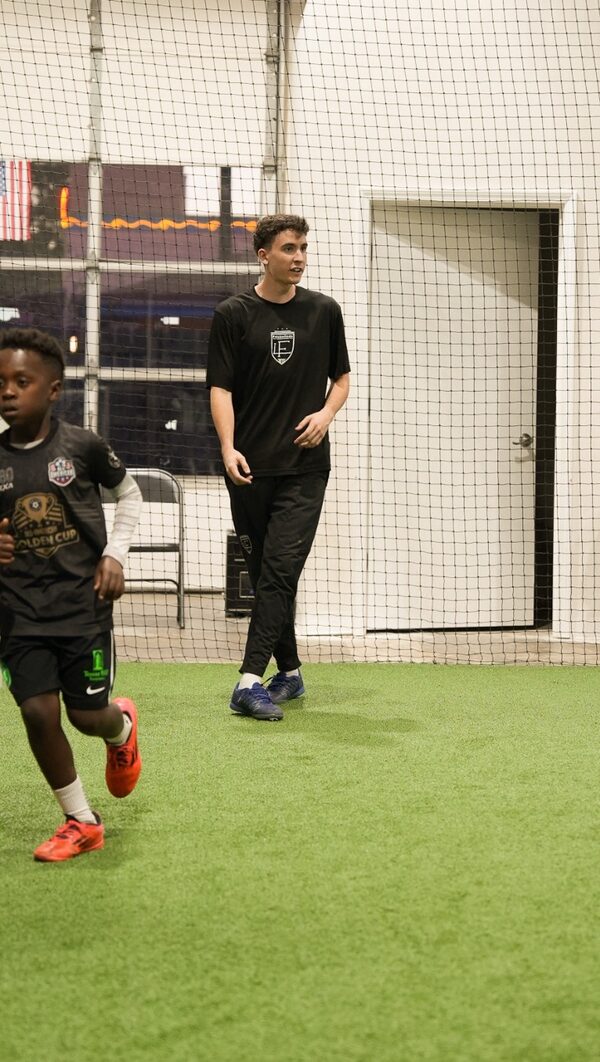 Elijah Lolla walking across the turf with a young player