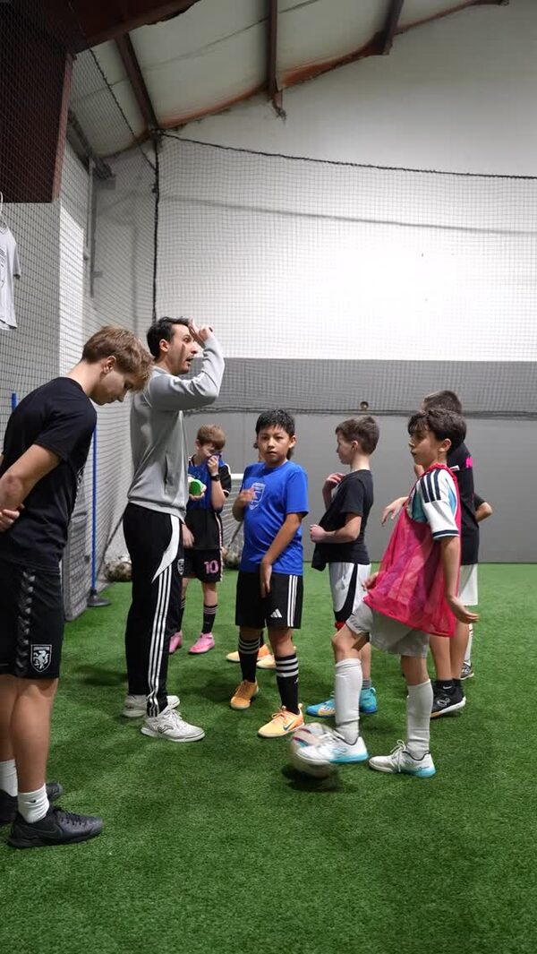 Elijah Lolla talking to a group of young players on the turf