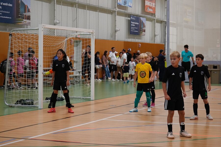 Futsal game on a hardwood court with a goal and spectators